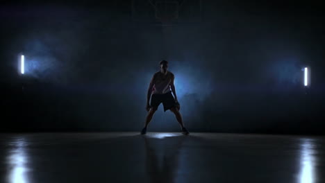 Jugador-De-Baloncesto-Regateando-En-La-Cancha-Con-La-Pelota-En-Una-Habitación-Oscura-Con-Luz-De-Fondo-En-Cámara-Lenta-En-El-Humo